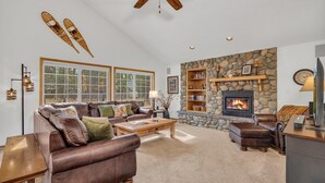 A spacious living room with a stone fireplace, leather furniture, and large windows. - Gosling Lane 6 (Bend)