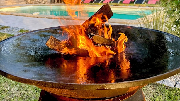 A poolside fire feature with a stone wall and lounge chairs in the background. - The butterflies of Quercy (Caylus)
