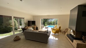 A modern living room with a sofa, a yellow armchair, a TV on a wooden stand, and a fireplace. - The butterflies of Quercy (Caylus)