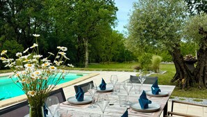 An outdoor dining area with a pool view, set tables with blue napkins, and a glass vase with flowers. - The butterflies of Quercy (Caylus)