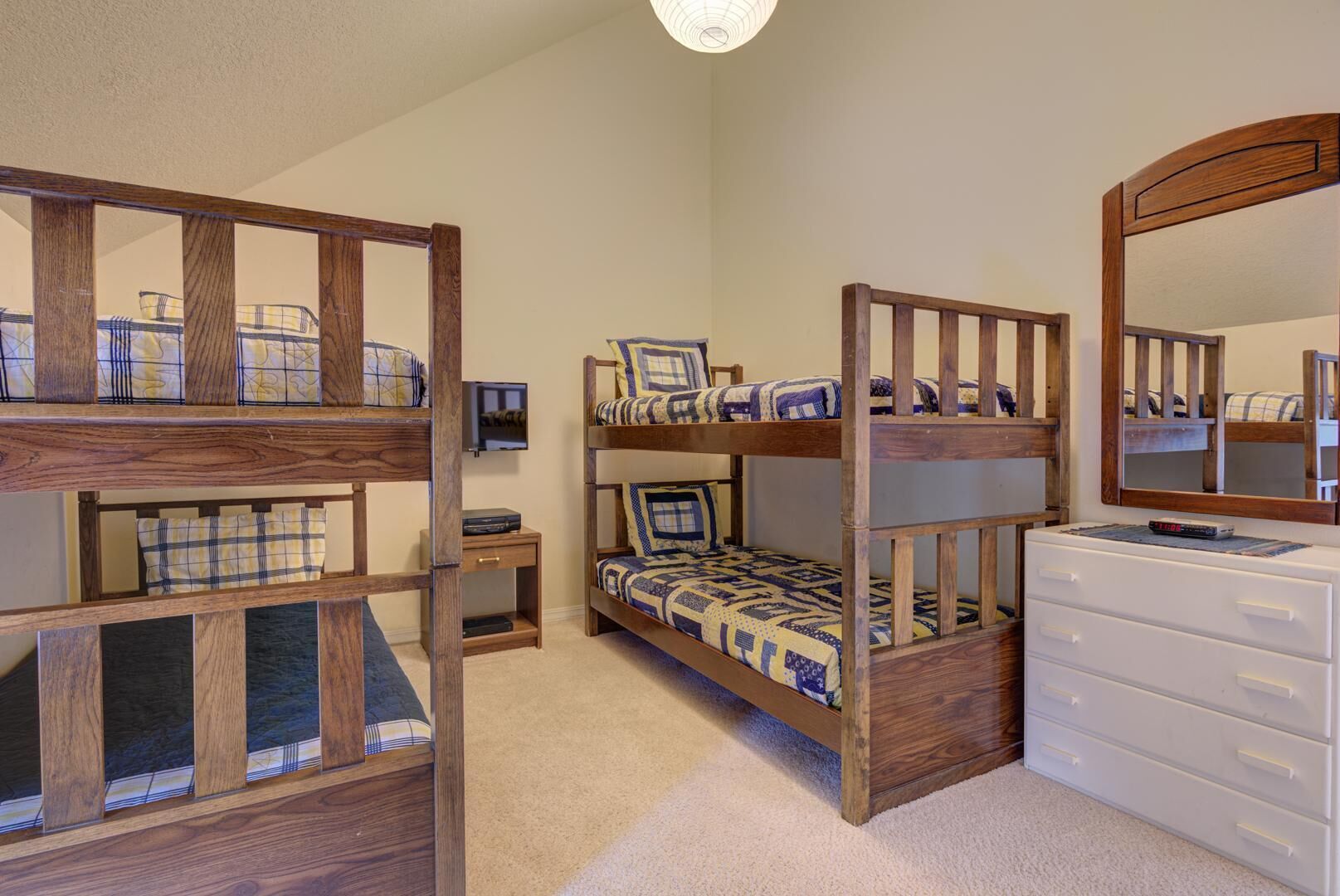 A bedroom with two bunk beds, a dresser, a television, and a mirror.