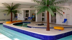 An indoor swimming pool with blue-tiled edges, two palm trees, and yellow floating rings.