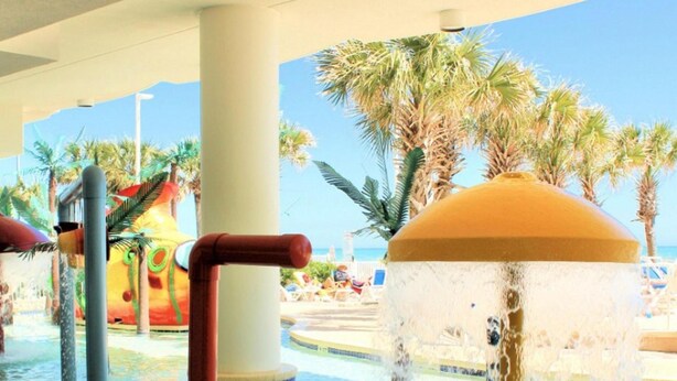 A water feature with a central column and surrounding palm trees.