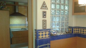 A kitchen with a gas stove, wooden cabinets, a tiled backsplash, and a window with decorative glass panes. - The River Lee Hotel in Cork (Espartinas)