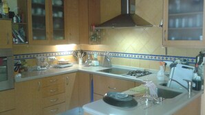 A kitchen with wooden cabinets, a gas stove, a sink, and a coffee maker. - The River Lee Hotel in Cork (Espartinas)