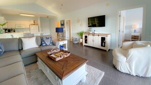 Een moderne woonkamer met een bank, salontafel en een aan de muur bevestigde televisie.