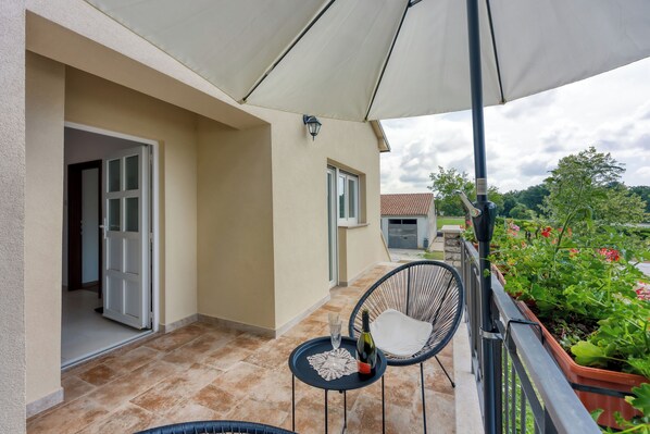 Un balcon avec une table, des chaises et une bouteille de vin.