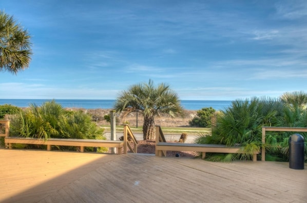 A wooden deck with a view of the beach and ocean.