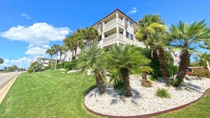 A multi-story hotel with balconies, surrounded by well-maintained lawns and palm trees. - Ocean Forest Villas by Palmetto Vacations (Myrtle Beach)