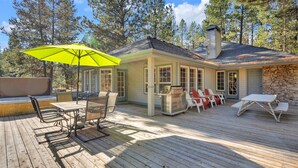 A covered outdoor deck with a table and chairs, a grill, and a yellow umbrella.