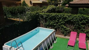 An outdoor swimming pool with a ladder, two lounge chairs, and a green lawn. - Los Alisos Country House (Guadalix de la Sierra)