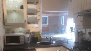 A compact kitchen with a washing machine, microwave, sink, and oven.