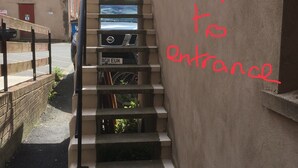 A narrow stairway with a metal handrail, leading to a building entrance.