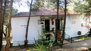 A small building with a tiled roof, surrounded by trees.