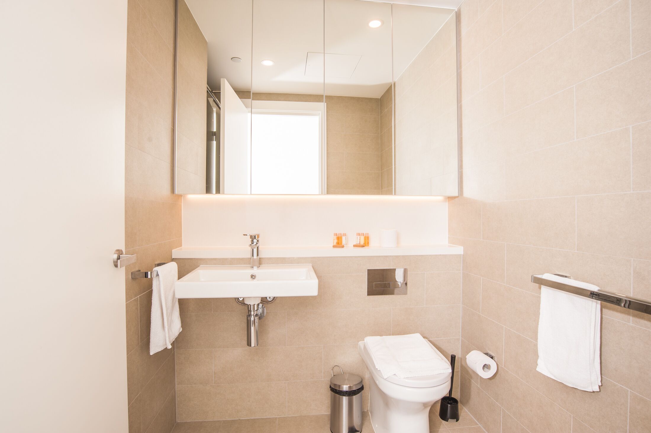 Un baño moderno con lavamanos, espejo y retrete.