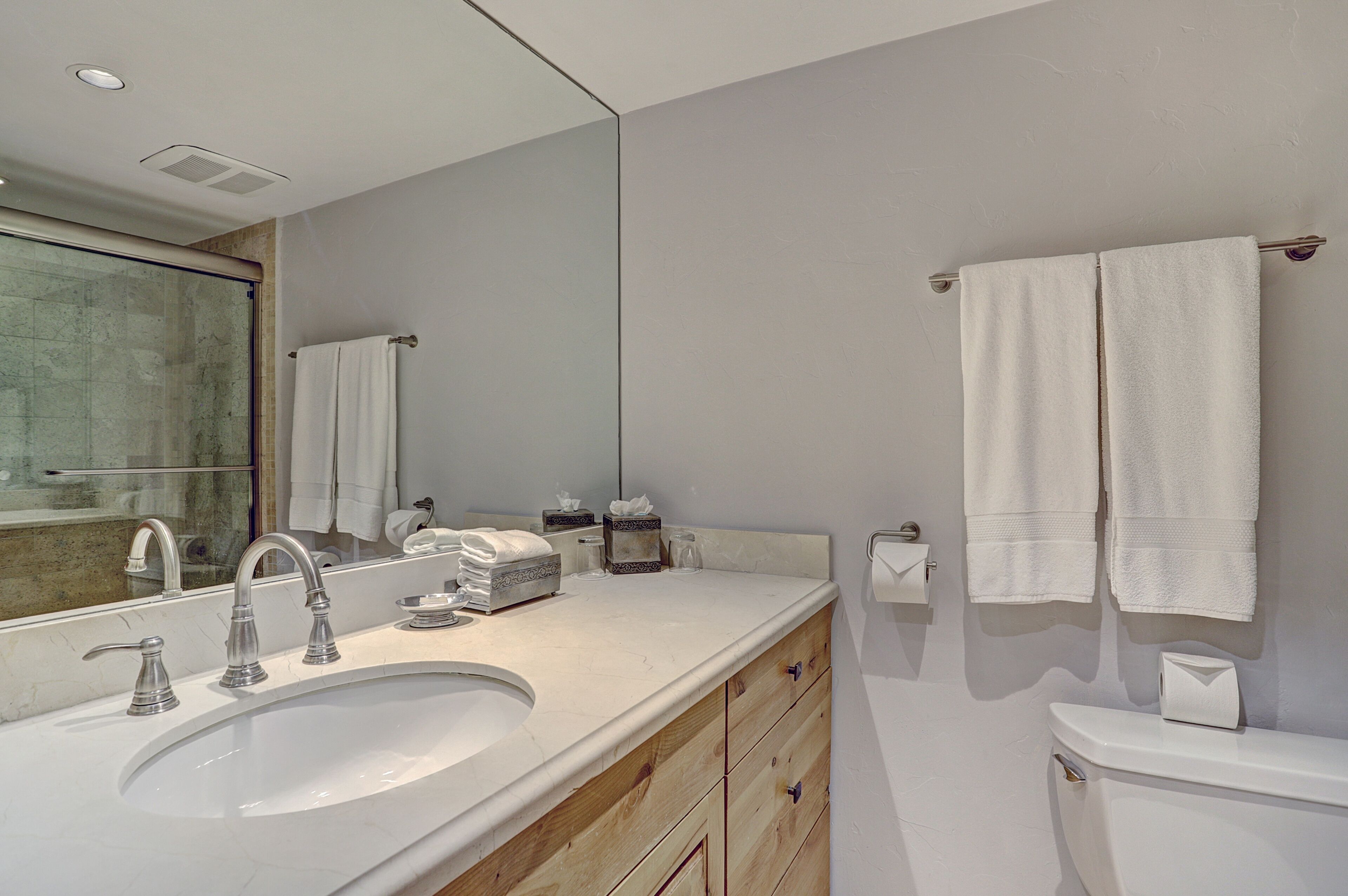 Un bagno moderno con uno specchio grande, un lavandino e un water.