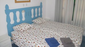 Ein Bett mit floral bedruckter Bettdecke, einem blauen Kopfteil und einem Kissen im gleichen Muster.