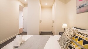 A hotel room with a bed, a nightstand, a lamp, and a painting on the wall. - Modern 2bed2bath APT at Neutral Bayparking+wifi (Neutral Bay)