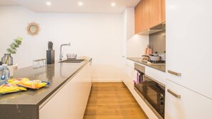 A modern kitchen with white cabinetry, a wooden countertop, and a built-in oven. - Modern 2bed2bath APT at Neutral Bayparking+wifi (Neutral Bay)