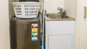 A compact laundry area with a washing machine, a dryer, a small sink, and a basket. - Modern 2bed2bath APT at Neutral Bayparking+wifi (Neutral Bay)