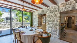 A dining area with a stone wall, wooden beams, and a table set for four. - House Carpe Diem (Jurdani)