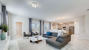 A modern living room with a grey sectional sofa, a white coffee table, and a grey patterned rug. - 1596 MC - Enchanted 6BR Villa: Pool, Magic for 14 (Davenport)