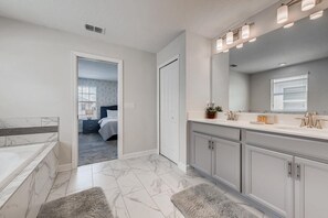Une salle de bain moderne avec un grand miroir, un meuble-lavabo et une baignoire.