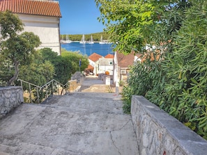 Eine Küstenstadt mit einer Steintreppe, die zu einem Uferbereich mit Segelbooten führt.
