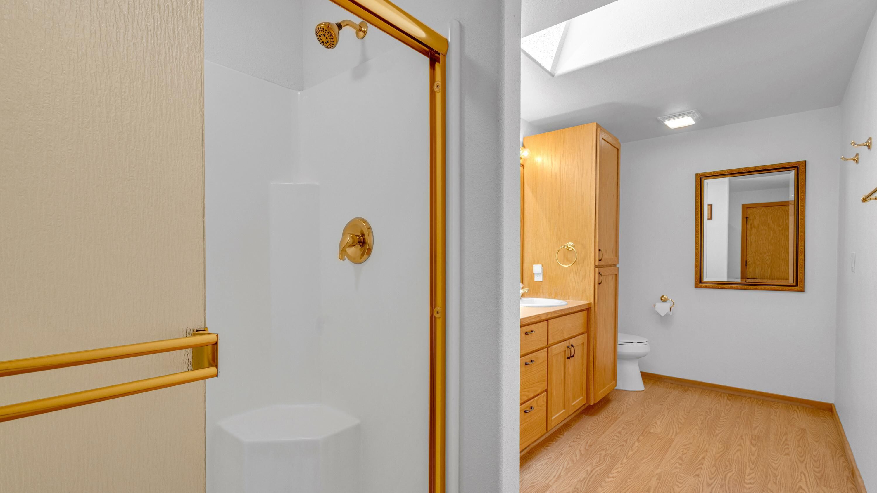 Une salle de bain avec douche, toilettes et meubles en bois.