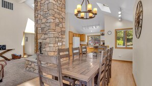 A spacious kitchen with a stone accent wall, wooden dining table, and chairs. - Lassen Lane 15 (Bend)