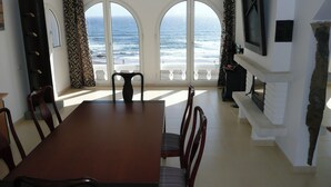 A dining area with a view of the ocean through large arched windows, a fireplace, and a television mounted on the wall. - Terrazas del Mar Villa on the Beach Sea Terrace Wifi Free Golf Ecological House (Telde)