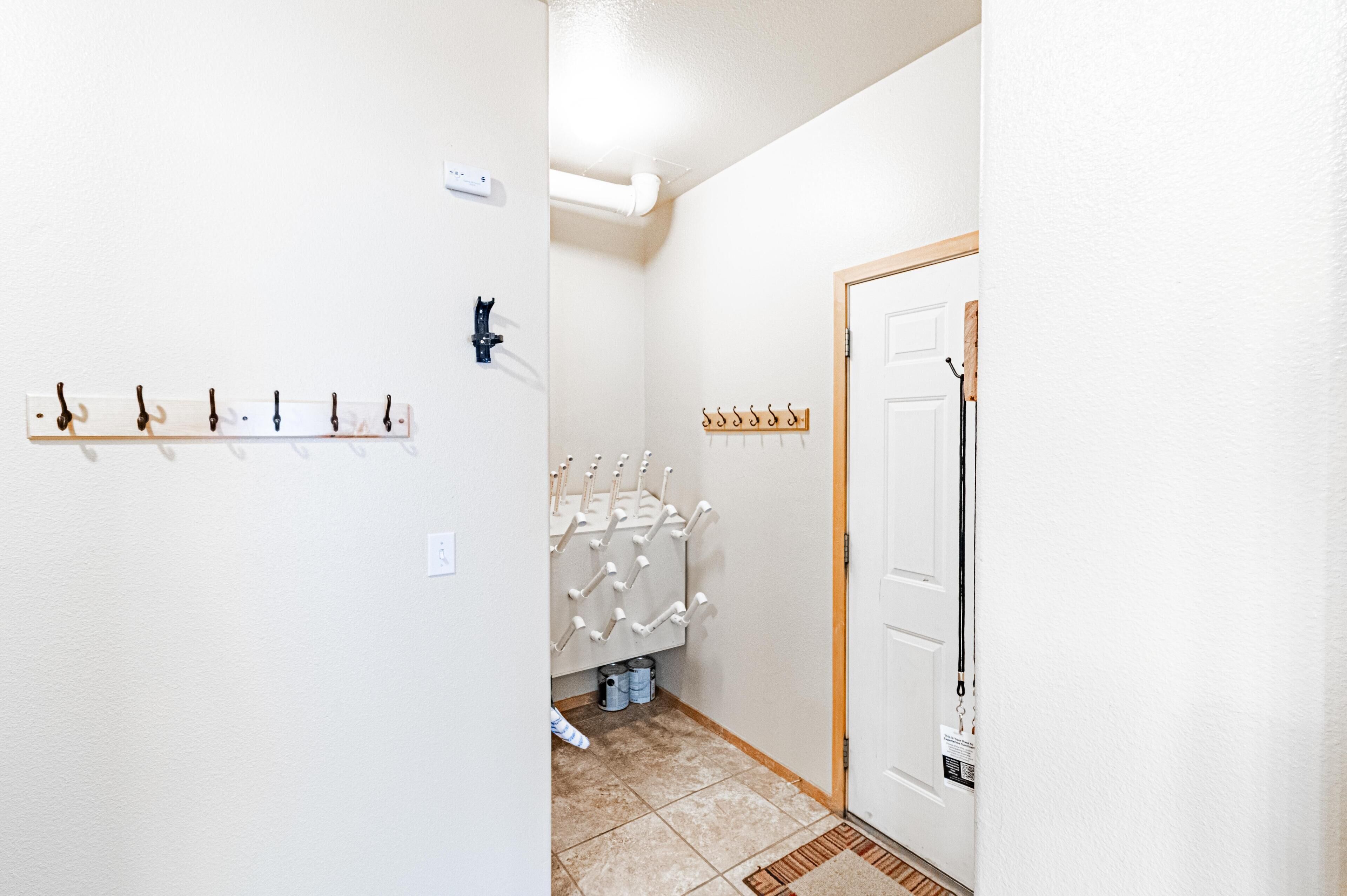 A hallway with a coat rack, a wall-mounted light switch, and a door with a coat hanging on the handle.
