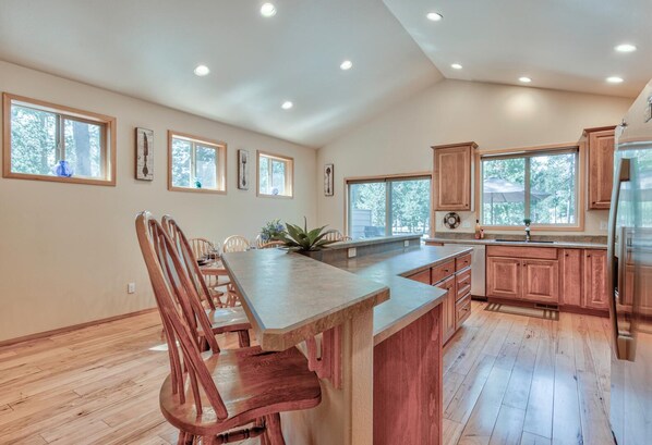 A spacious kitchen with wooden cabinets, a large island, and multiple windows providing natural light. - Splitrock Lane 3 (Bend)