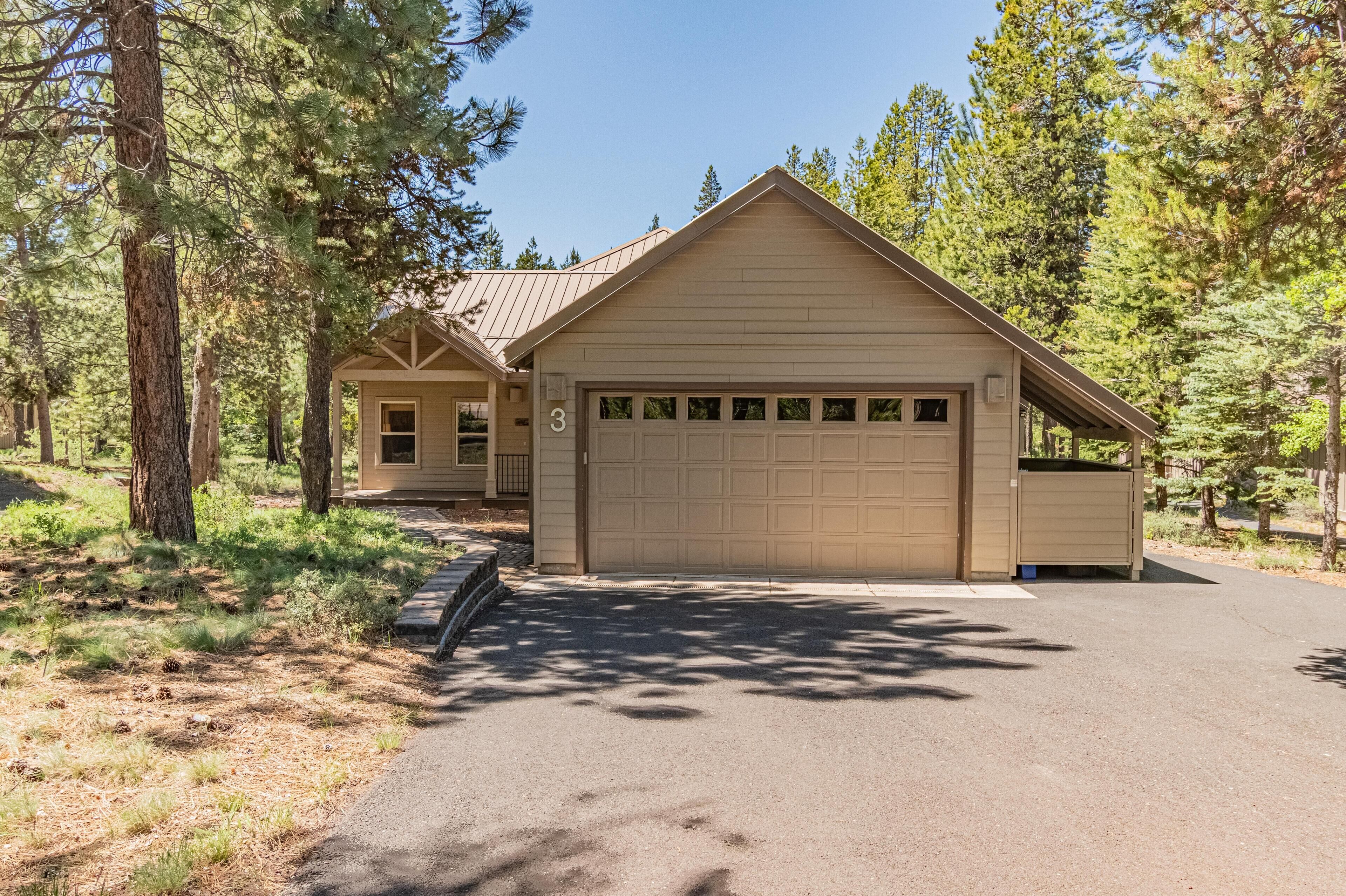 A single-story house with a garage, surrounded by trees.