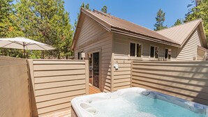 Une cabane en bois dotée d’un bain à remous et d’une terrasse couverte.