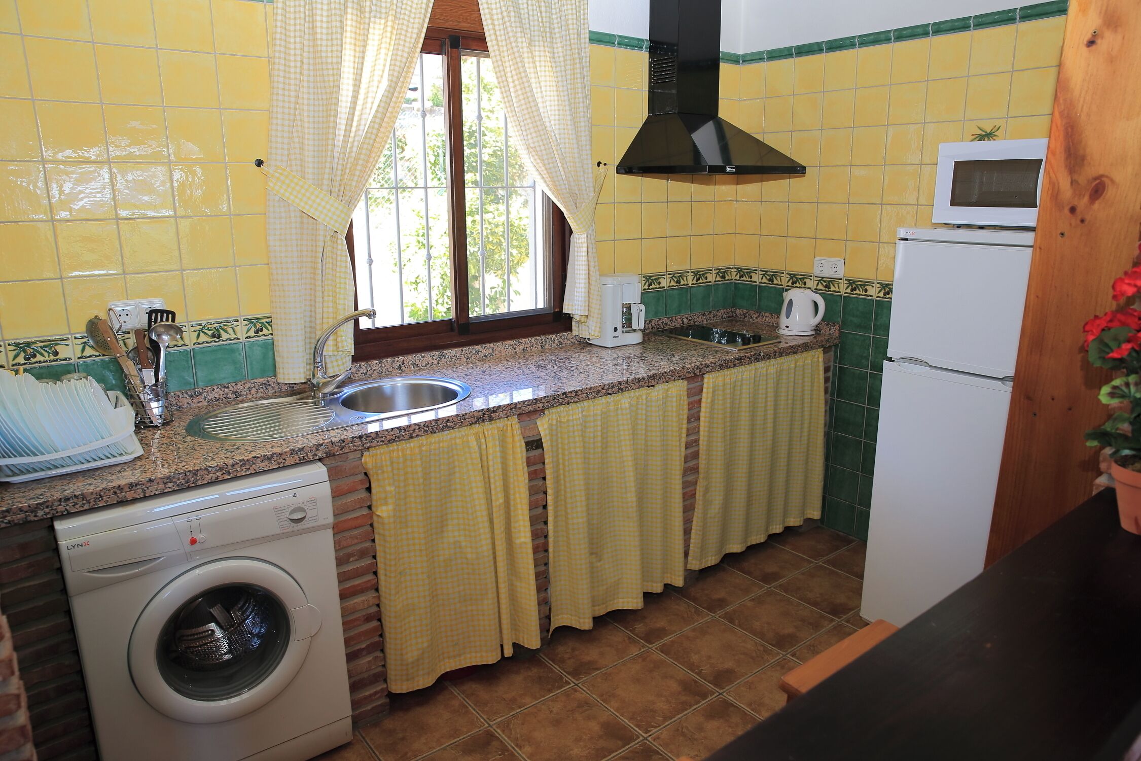A compact kitchen with a washing machine, a microwave, and a refrigerator.