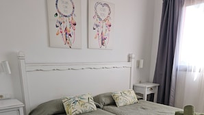 A neatly made bed with a green quilt, two pillows with a leaf pattern, and rolled towels on the bed. - Nice Apartments With 3 Swimming Pools Wifi (La Oliva)