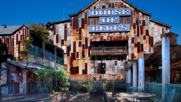 A building with a sign reading "HOUSE OF BLUES" featuring a rustic, wooden facade with a balcony and outdoor seating area. - Caravelle Resort by Palmetto Vacations (Myrtle Beach)