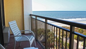 A balcony with a white chair, a view of the ocean, and a railing. - Caravelle Resort by Palmetto Vacations (Myrtle Beach)