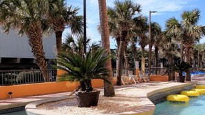 A pool area with multiple yellow inflatable rings, palm trees, and a tiled edge. - Caravelle Resort by Palmetto Vacations (Myrtle Beach)