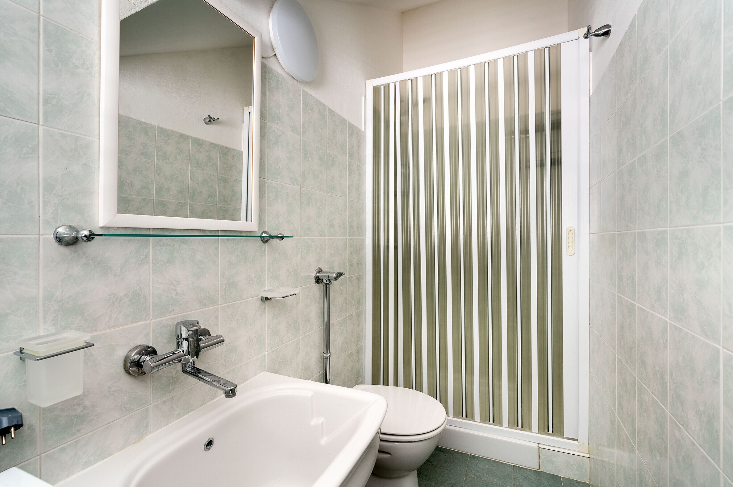 A bathroom with a bathtub, toilet, and a shower enclosure.
