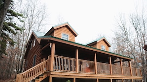 A wooden cabin with a covered deck and a staircase leading to the entrance. - Log Home in a Peaceful Wood in Jim Thorpe (Jim Thorpe)