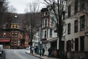 A street view with historic buildings, a corner shop, and parked cars. - Log Home in a Peaceful Wood in Jim Thorpe (Jim Thorpe)