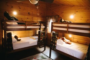 A cabin with two bunk beds, wooden walls, and a ceiling fan. - Log Home in a Peaceful Wood in Jim Thorpe (Jim Thorpe)