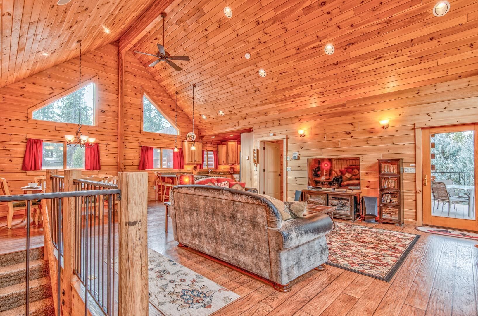 A spacious log cabin interior with a large sofa, dining area, and a cozy fireplace.