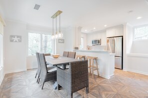A modern kitchen with white cabinetry, a stainless steel refrigerator, and a bar area.