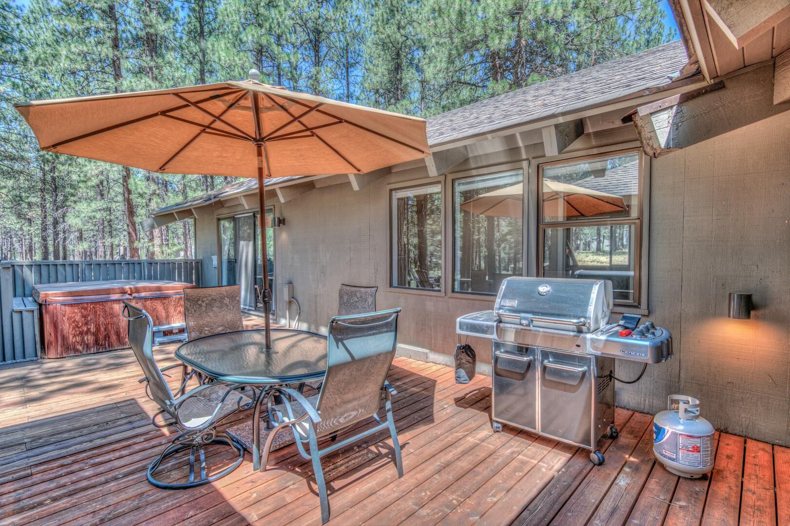 An outdoor deck with a glass table and chairs, a barbecue grill, and a propane tank.