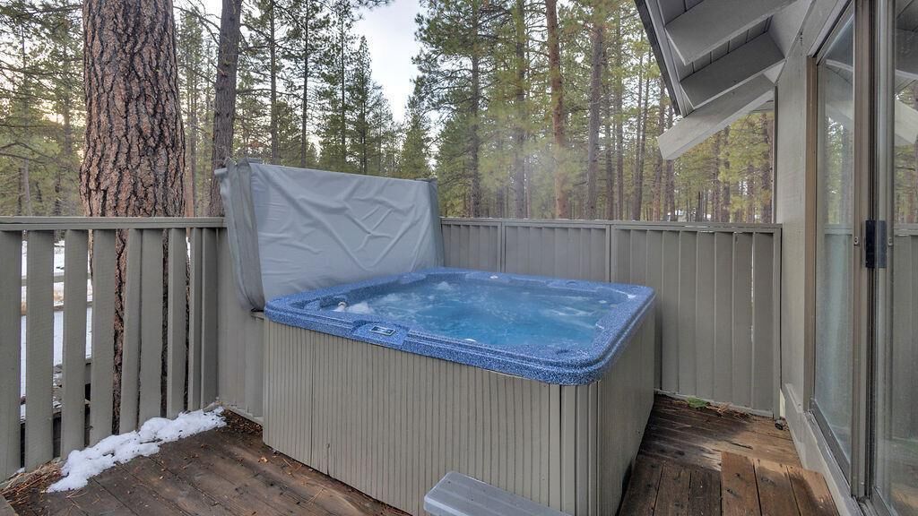 A hot tub on a wooden deck with a view of a forest.