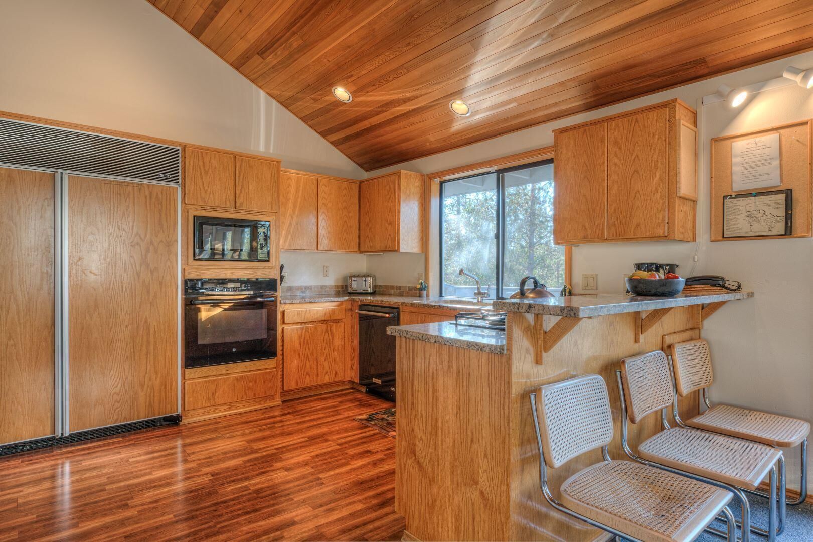 Una cucina moderna con mobili in legno, forno integrato e un'ampia finestra che lascia entrare molta luce naturale.