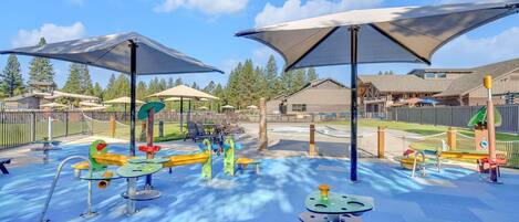 A playground with various play structures, shaded areas, and a fenced play area.
